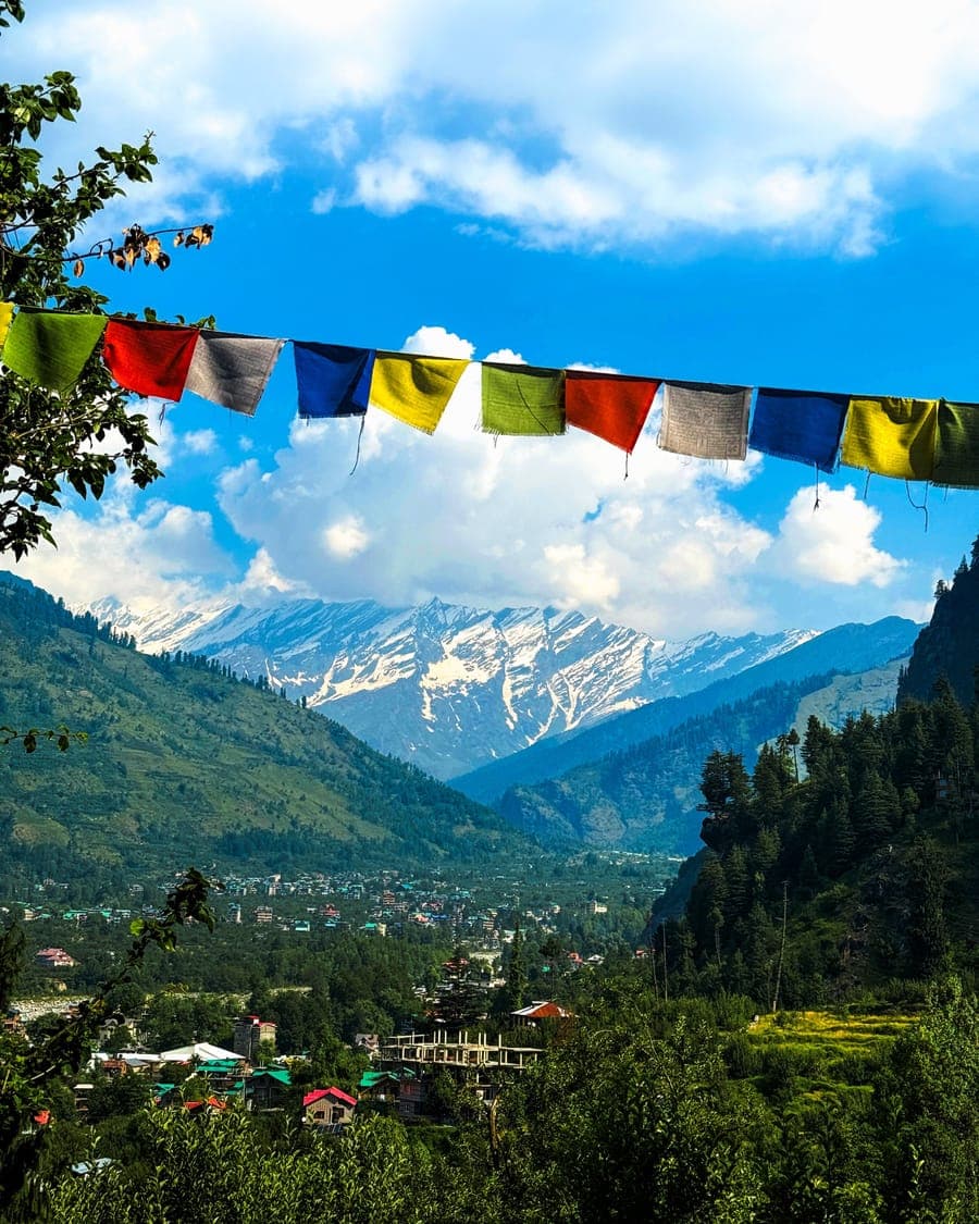 Prayer flags strung above a snow-capped Himalayan valley near Manali